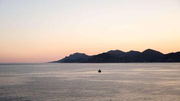 A calm sea with a boat in the distance and mountains in the background.