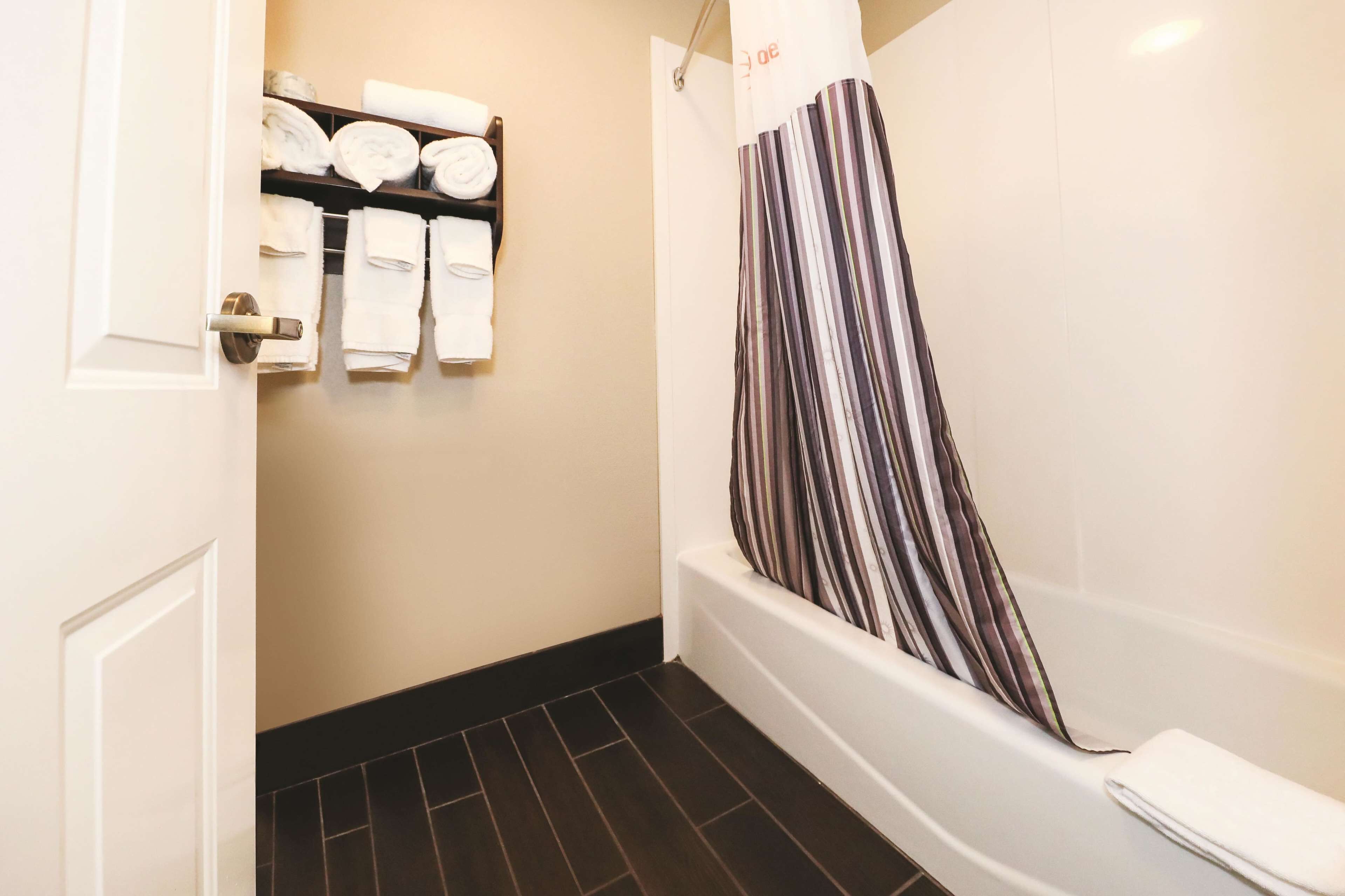A bathroom with a bathtub, a towel rack with neatly folded towels, and a striped shower curtain.