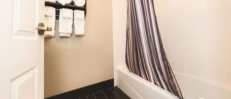 A bathroom with a bathtub, a towel rack with neatly folded towels, and a striped shower curtain.