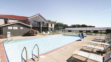 A swimming pool with lounge chairs and a lifeguard stand.