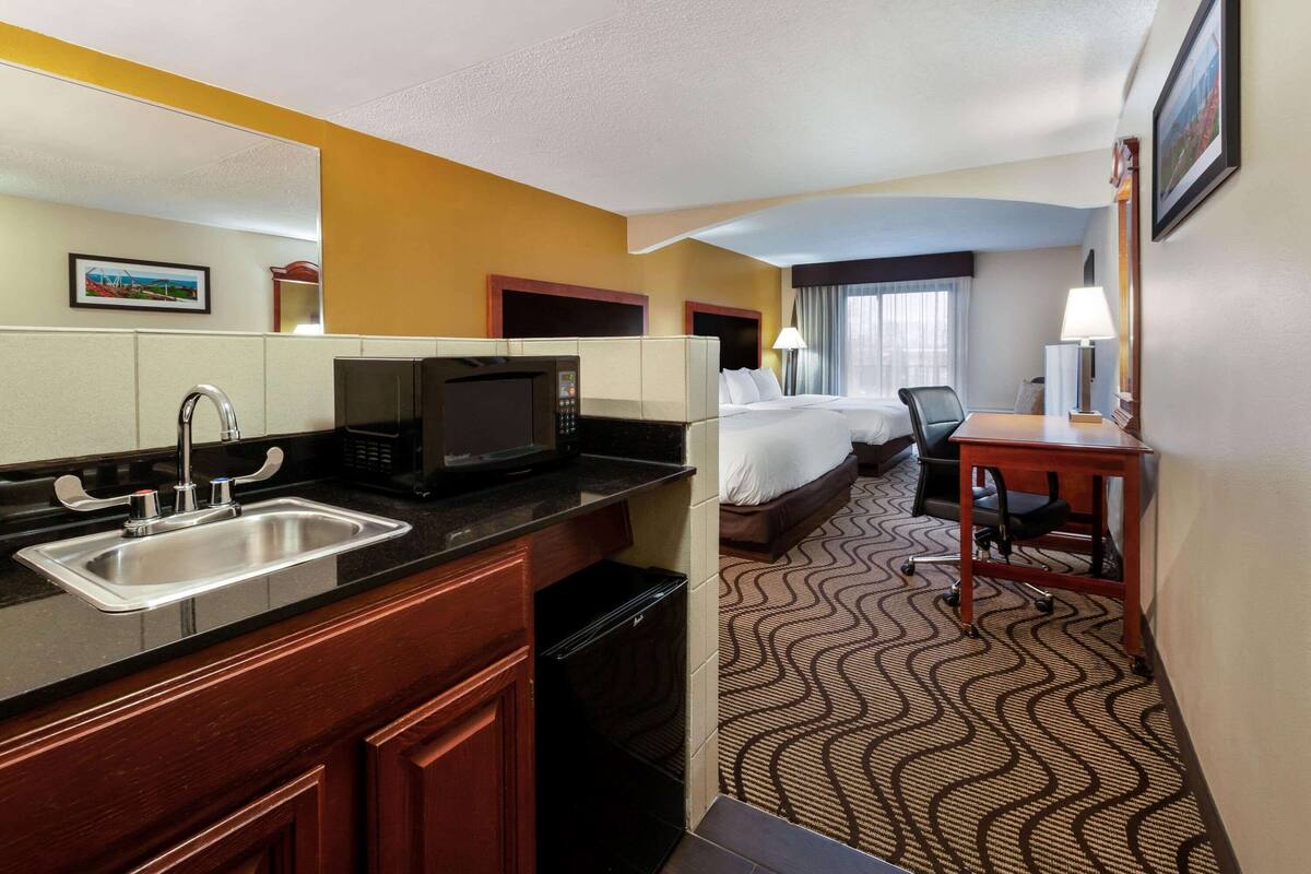Habitación de hotel con kitchenette, cama, escritorio y baño.