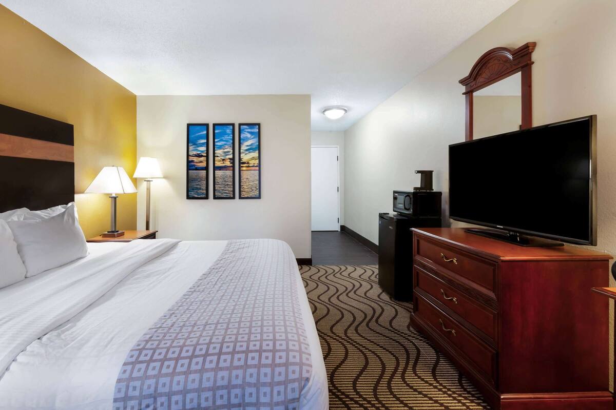 Una habitación de hotel con cama, cómoda, televisor y decoración en la pared.