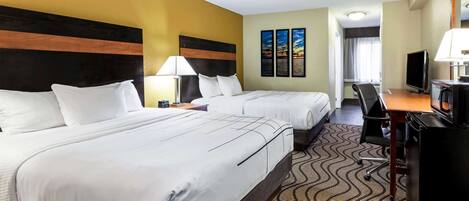 A hotel room with two beds, a desk with a computer, a TV, and a microwave.