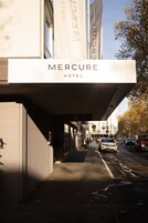 La fachada del Hotel Mercure, con una vista clara de la entrada y la calle frente al hotel.
