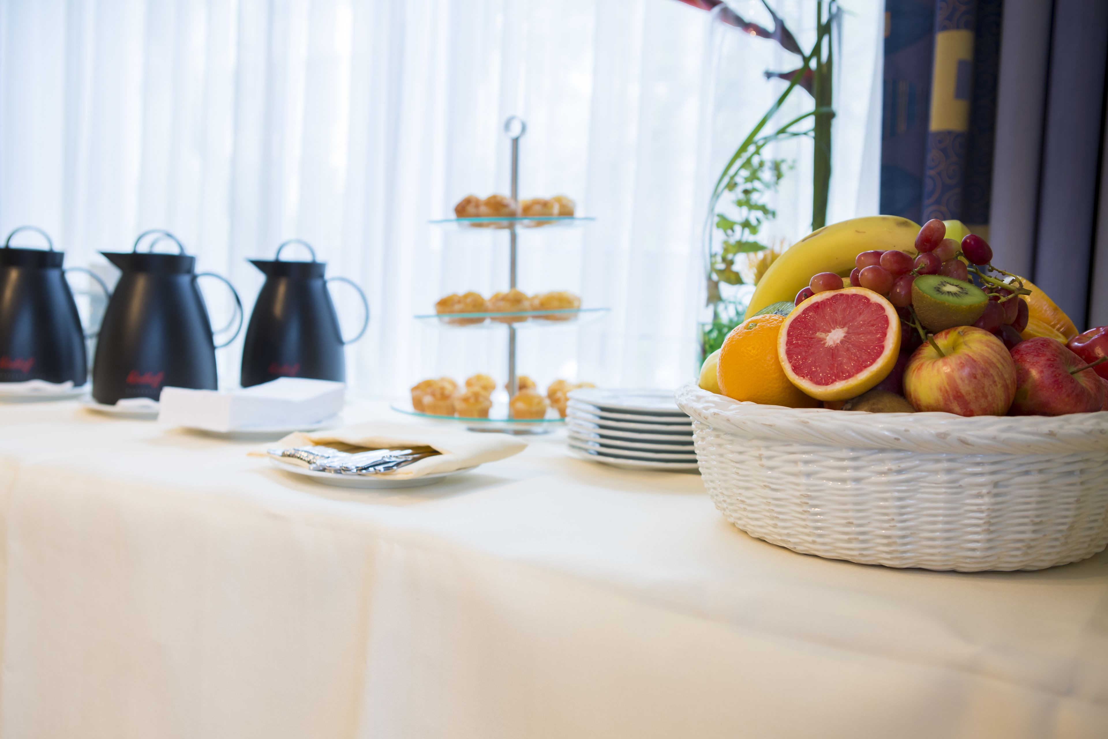 Un buffet de petit-déjeuner proposant une variété de viennoiseries, de fruits et différentes sortes de café.