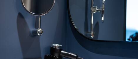 A modern bathroom with a round mirror, a white sink, and a handheld showerhead.