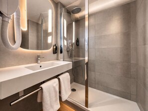 Un baño moderno con un espejo grande, lavamanos dobles, cabina de ducha de vidrio y un perchero para toallas.