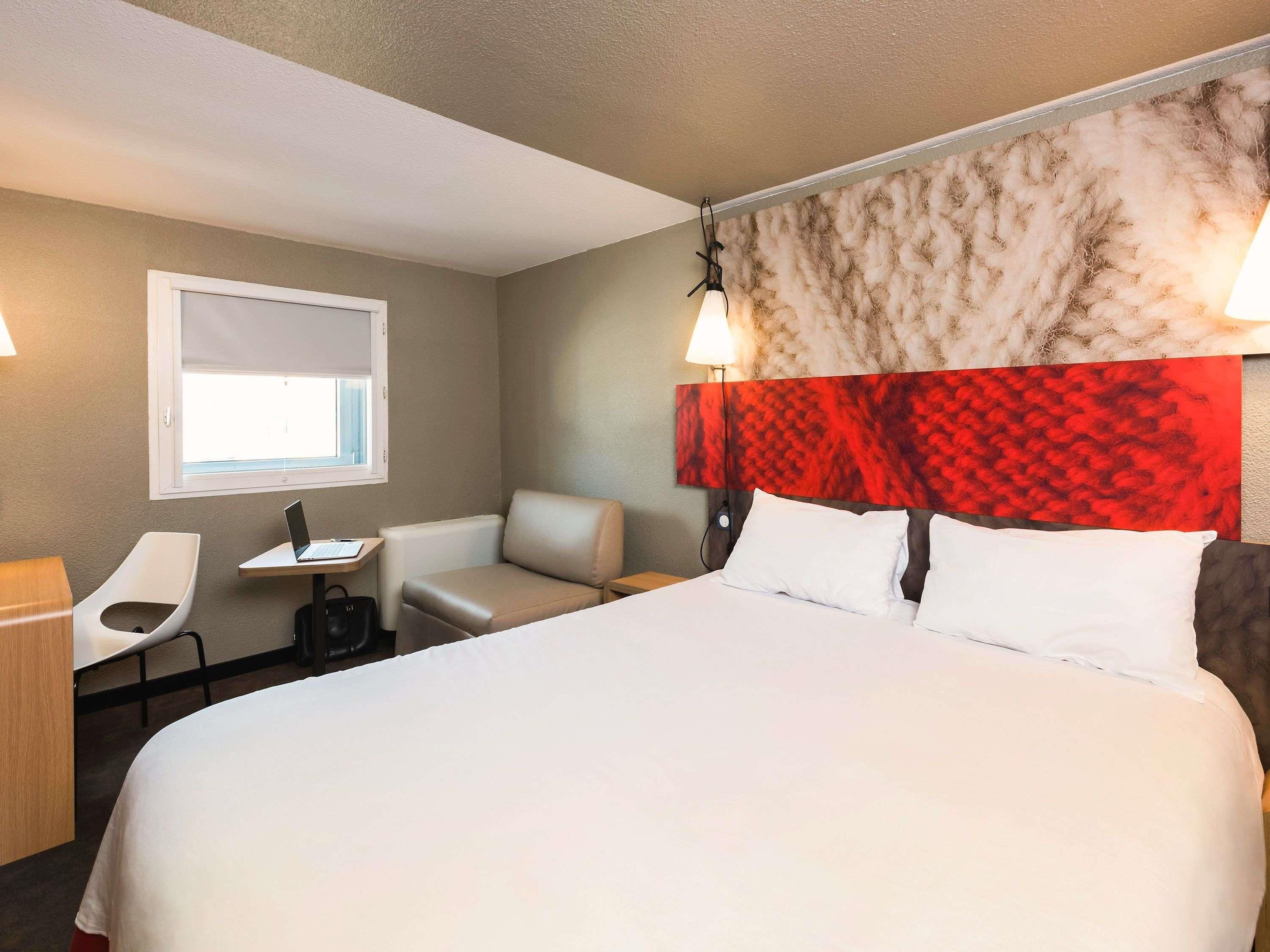 Een hotelkamer met een bed, een bureau, een stoel en een raam.