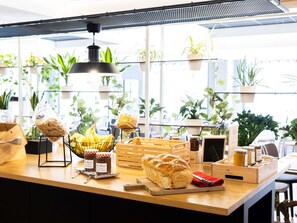 A bakery counter with bread, bananas, jars of jam, and a basket of bread. - ibis Bordeaux Centre Meriadeck (Bordeaux)