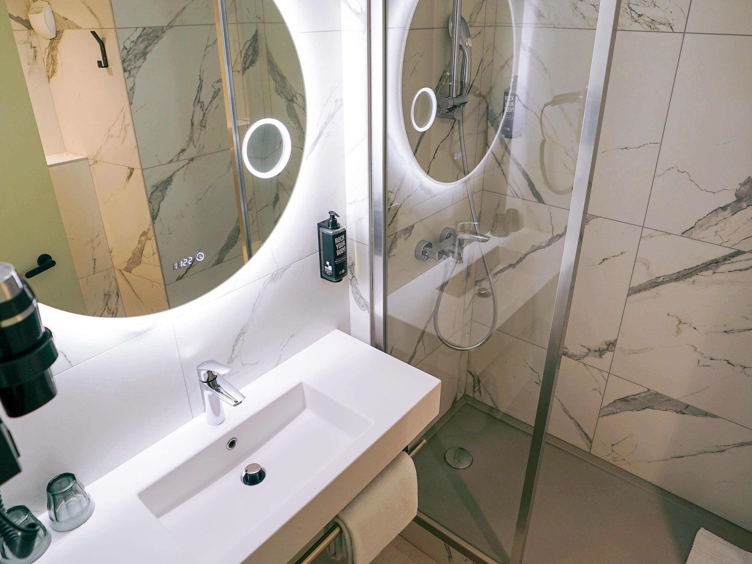 A bathroom with a white sink, a mirror, and a shower area.