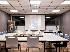 A conference room with a large screen displaying 'WORK WORK WORK!' and a poster with 'WORK WORK WORK!' on the wall. - ibis Bordeaux Centre Meriadeck (Bordeaux)