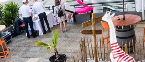 An outdoor patio area with a wooden fence, potted plants, a giraffe statue, and a red umbrella.