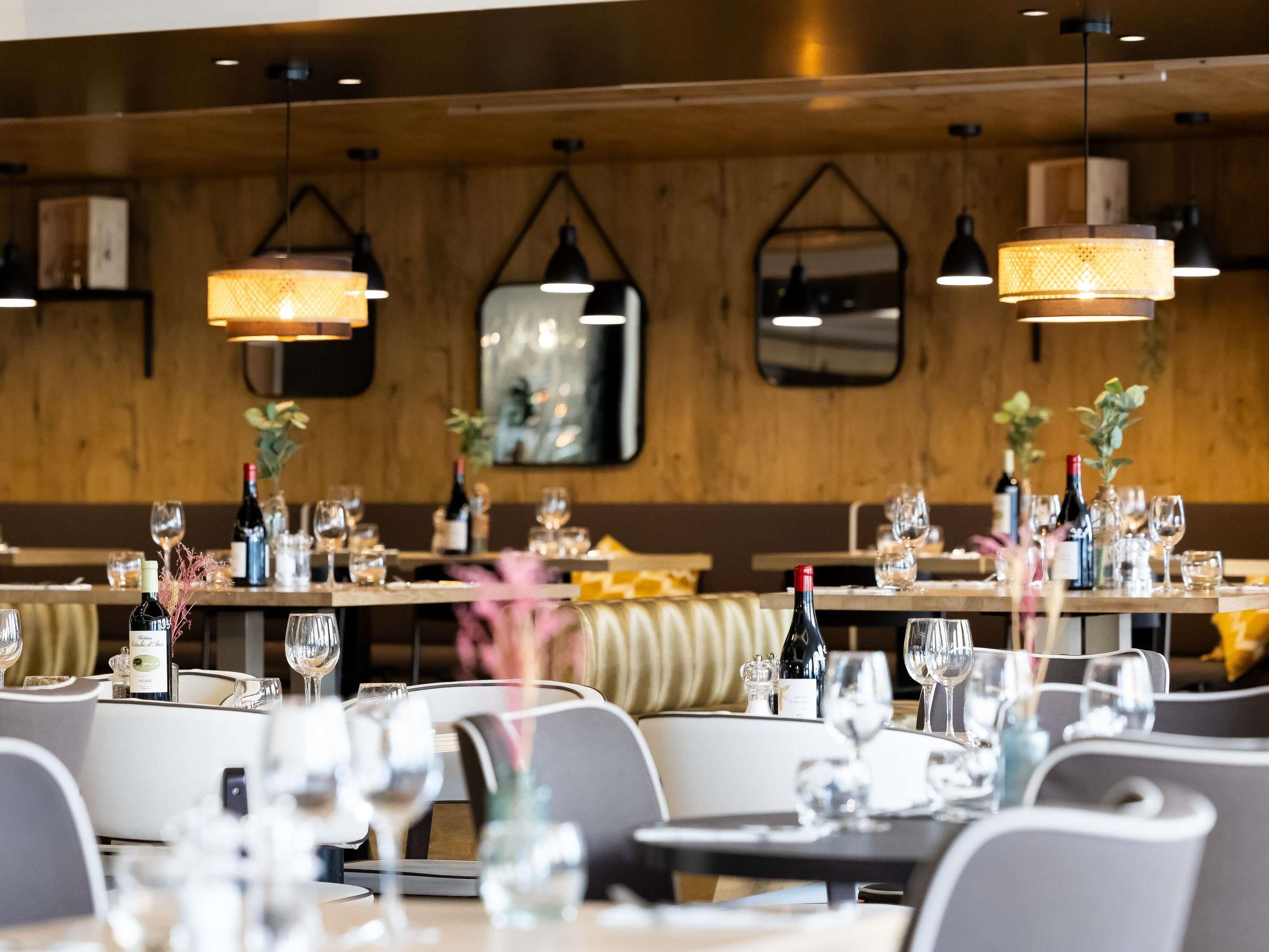 Een restaurantinterieur met gedekte tafels, wijnglazen en flessen.