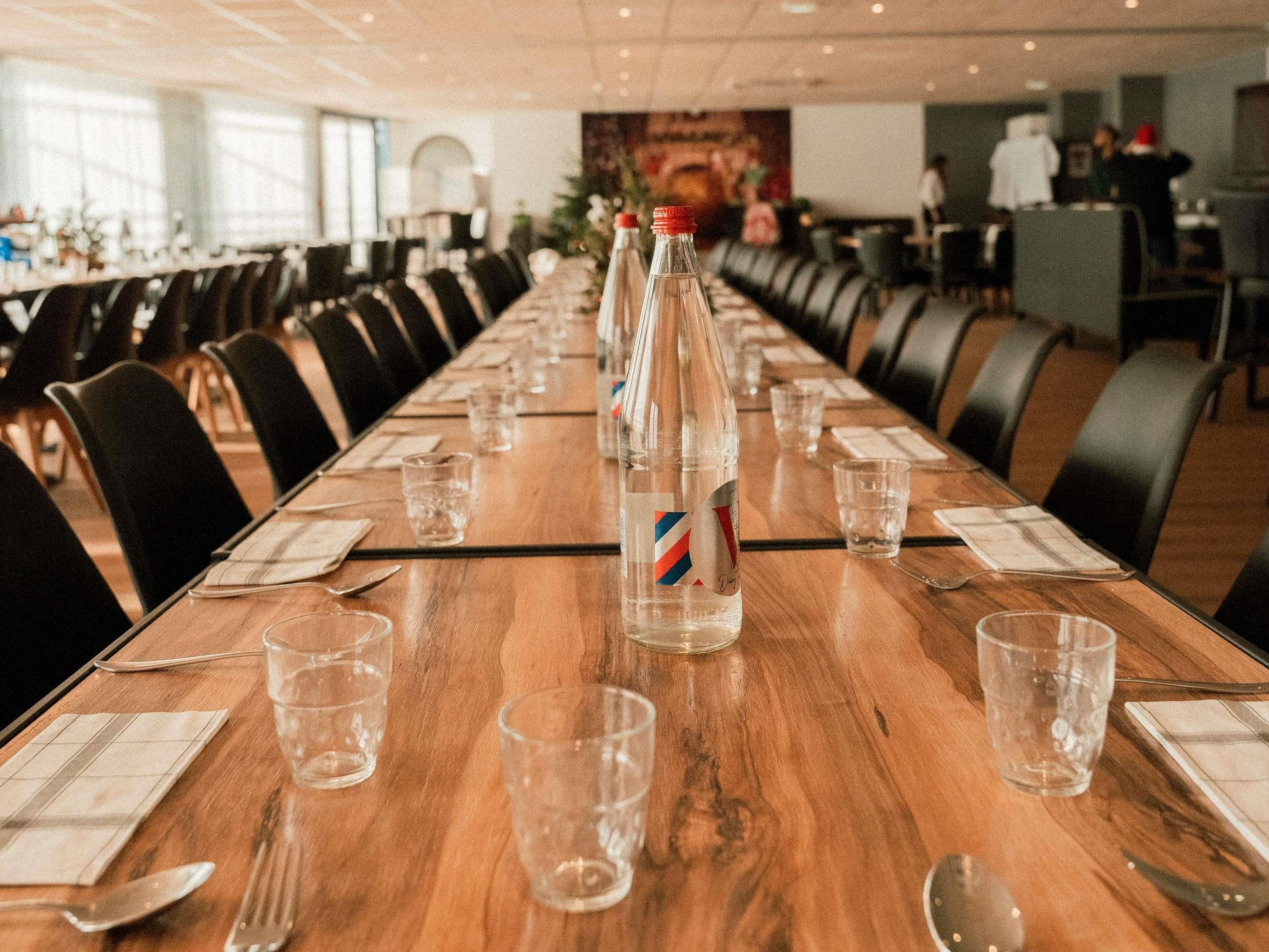 A conference room with long tables, chairs, and water bottles.