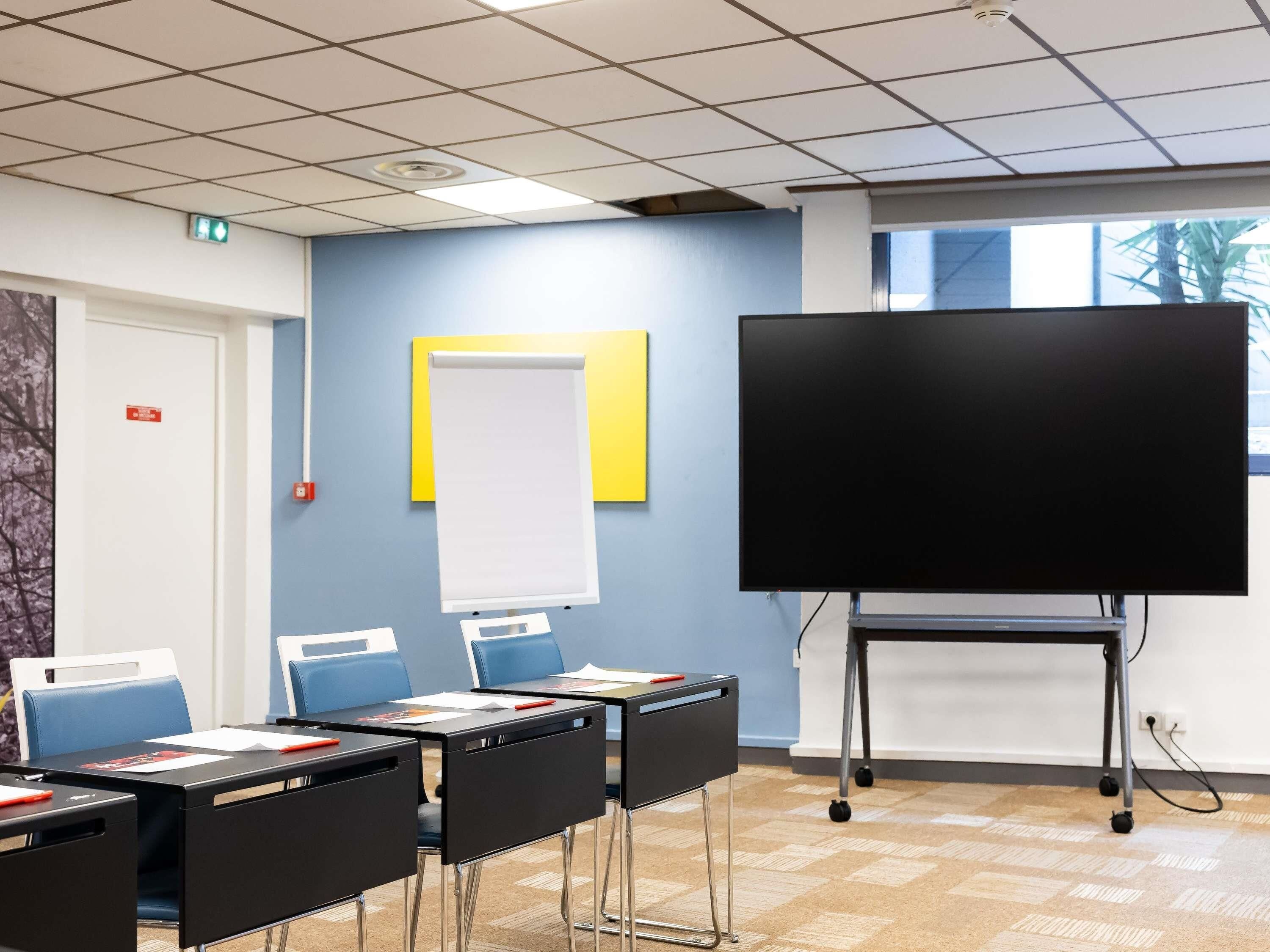 A classroom with desks, chairs, a whiteboard, and a projection screen.