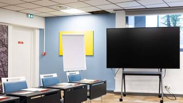 A classroom with desks, chairs, a whiteboard, and a projection screen.