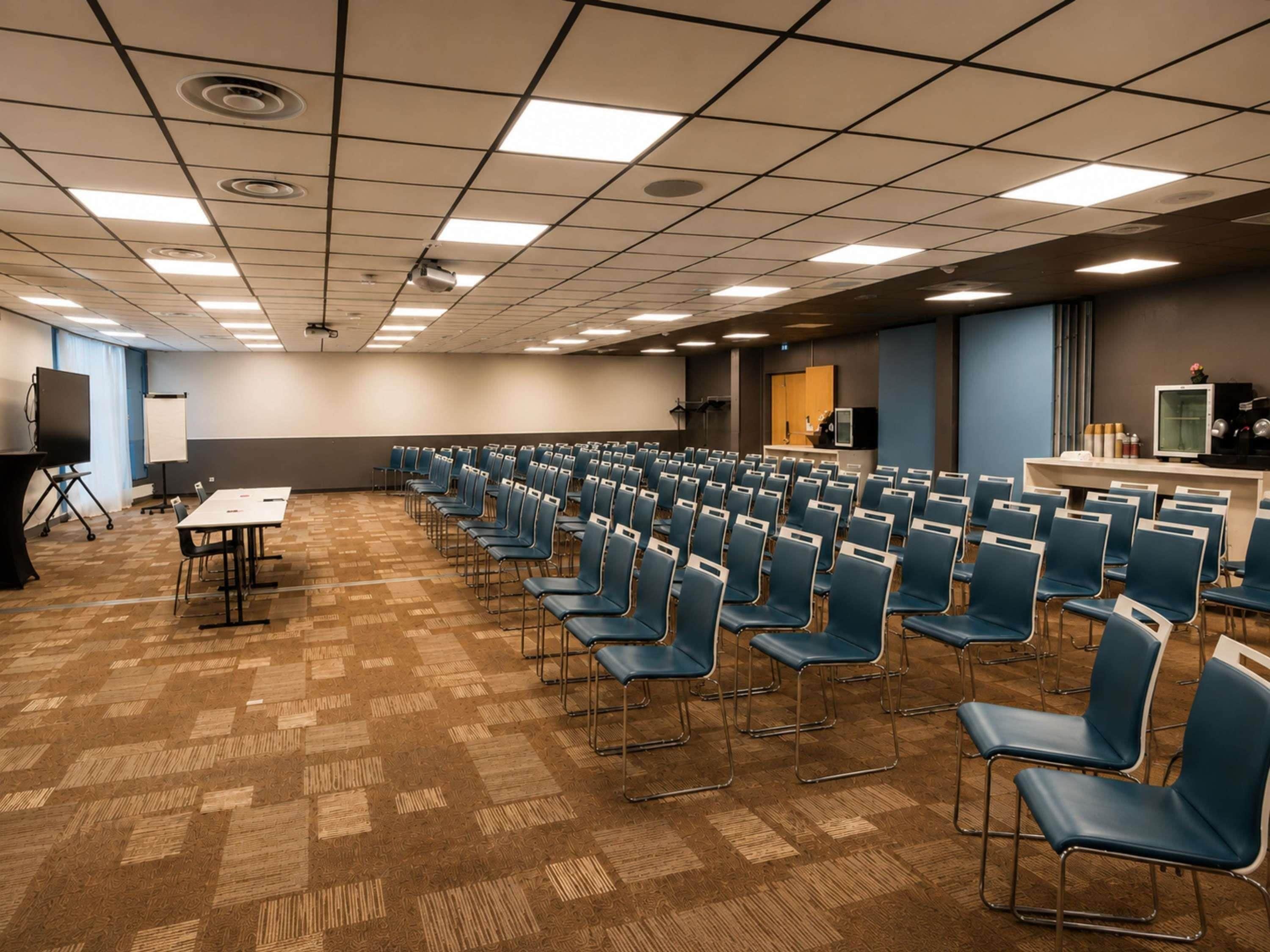 A conference room with rows of chairs, a whiteboard, and presentation equipment.