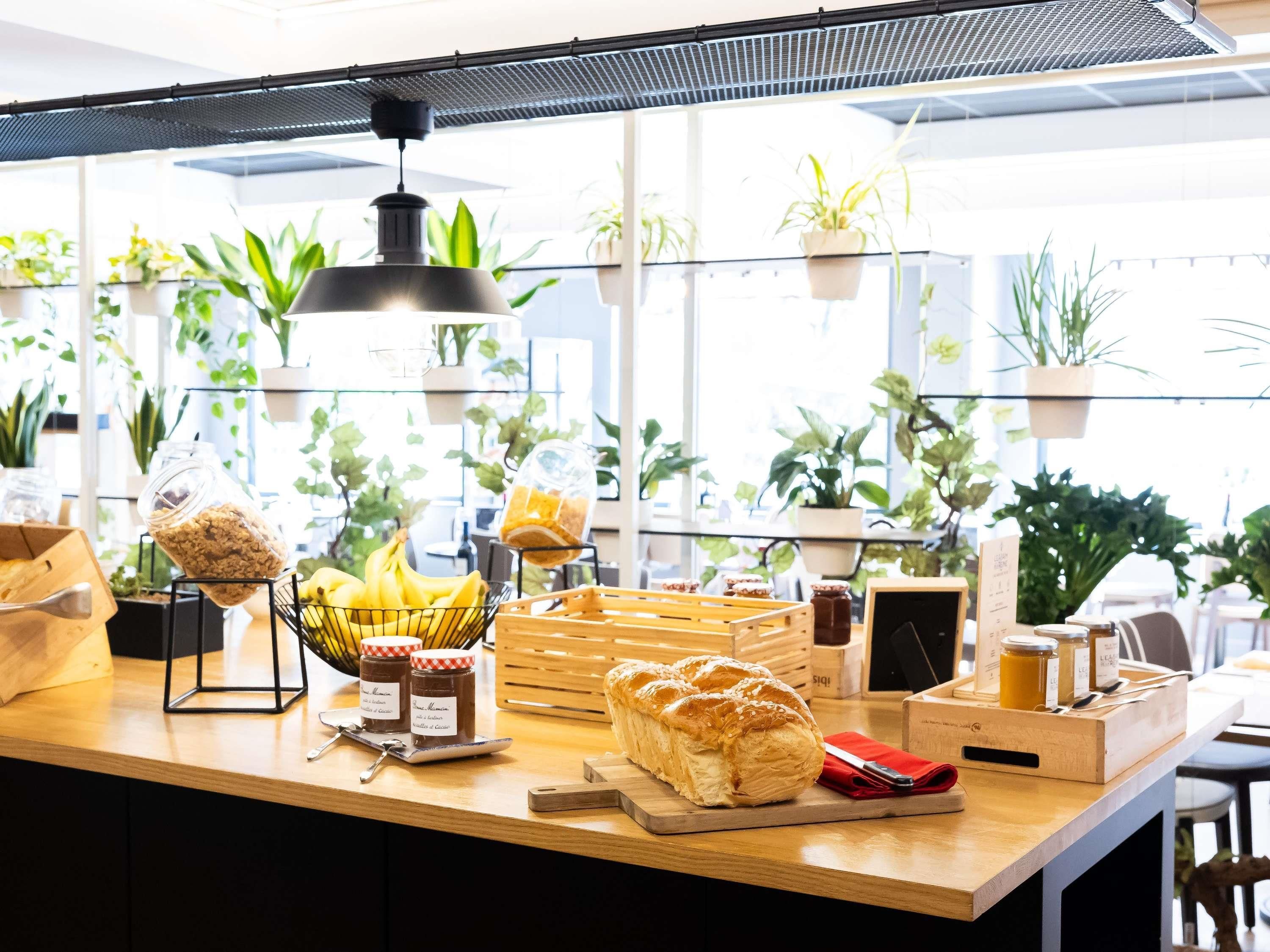 Eine Bäckereitheke mit Brot, Bananen, Marmeladengläsern und einem Brotkorb.
