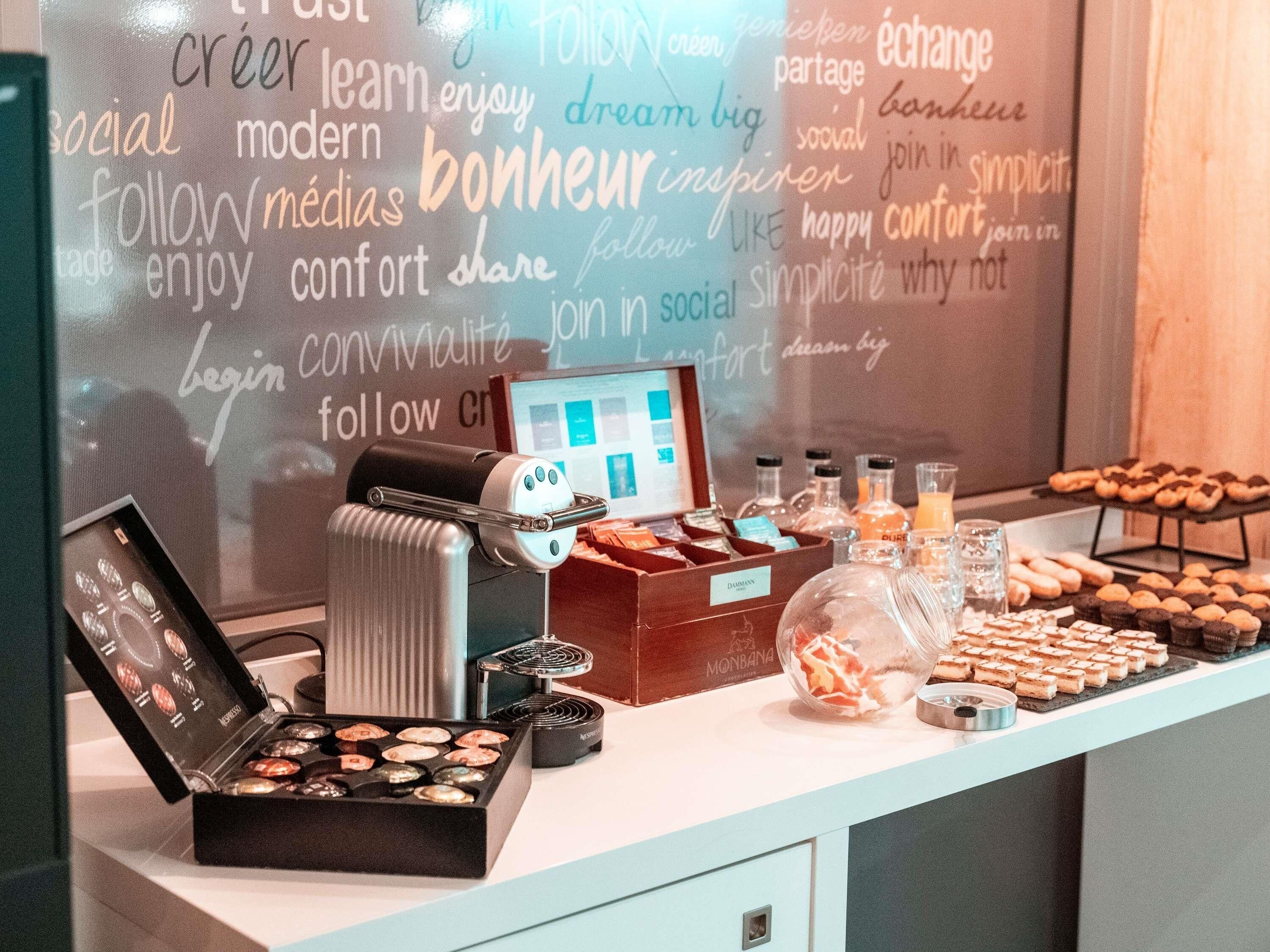 A coffee station with a coffee machine, a variety of pastries, and a selection of bottled beverages.