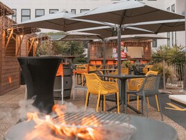 Un patio al aire libre con mesas, sillas, una parrilla y sombrillas.