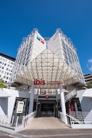 El exterior del hotel ibis, con una entrada destacada, un área cubierta con antenas parabólicas y un cielo azul despejado.