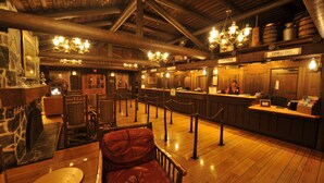 A wooden interior with a bar area, wooden ceiling beams, and a red leather chair. - The Cabins at Disney's Fort Wilderness Resort (Lake Buena Vista)