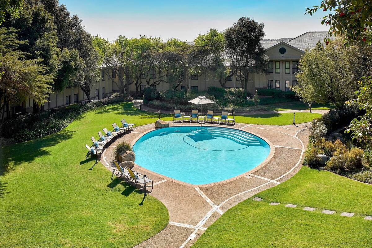 A swimming pool with lounge chairs and a building in the background.