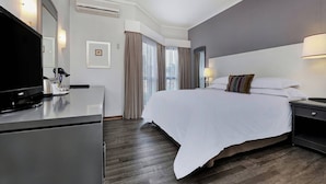 A hotel room with a bed, a TV on a desk, a lamp, and a picture frame on the wall. - Protea Hotel by Marriott Midrand (Midrand)