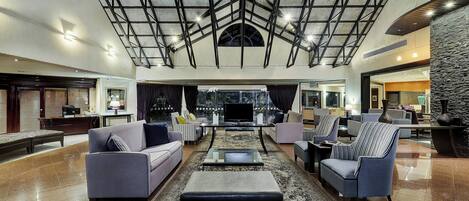 A spacious lobby with a high ceiling, a central seating area, and a television.
