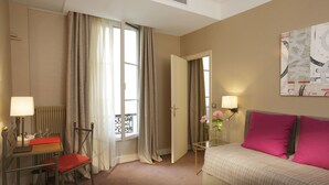 A hotel room with a bed, a desk with a chair, a lamp, a window with curtains, and a painting on the wall. - Hôtel Londres et New York - Teritoria (Paris)