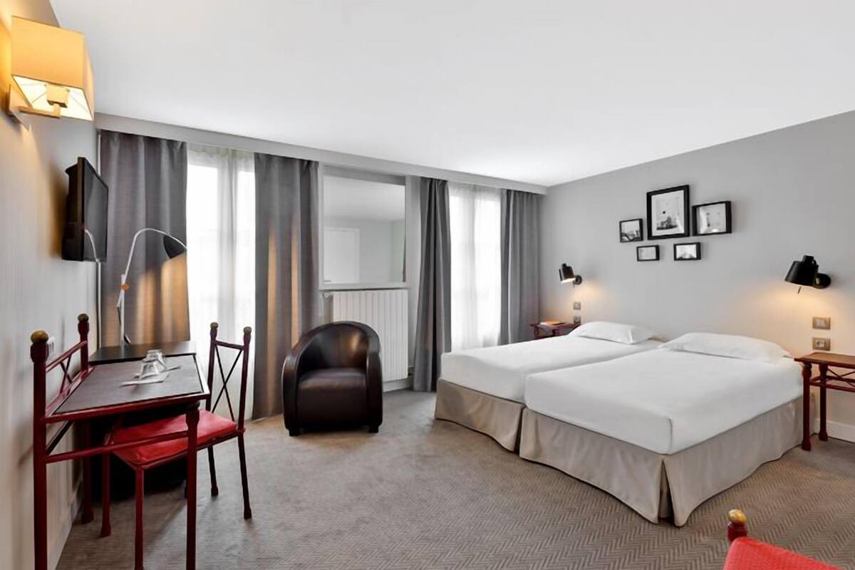 Een hotelkamer met twee bedden, een bureau met stoel, een bank en een televisie.