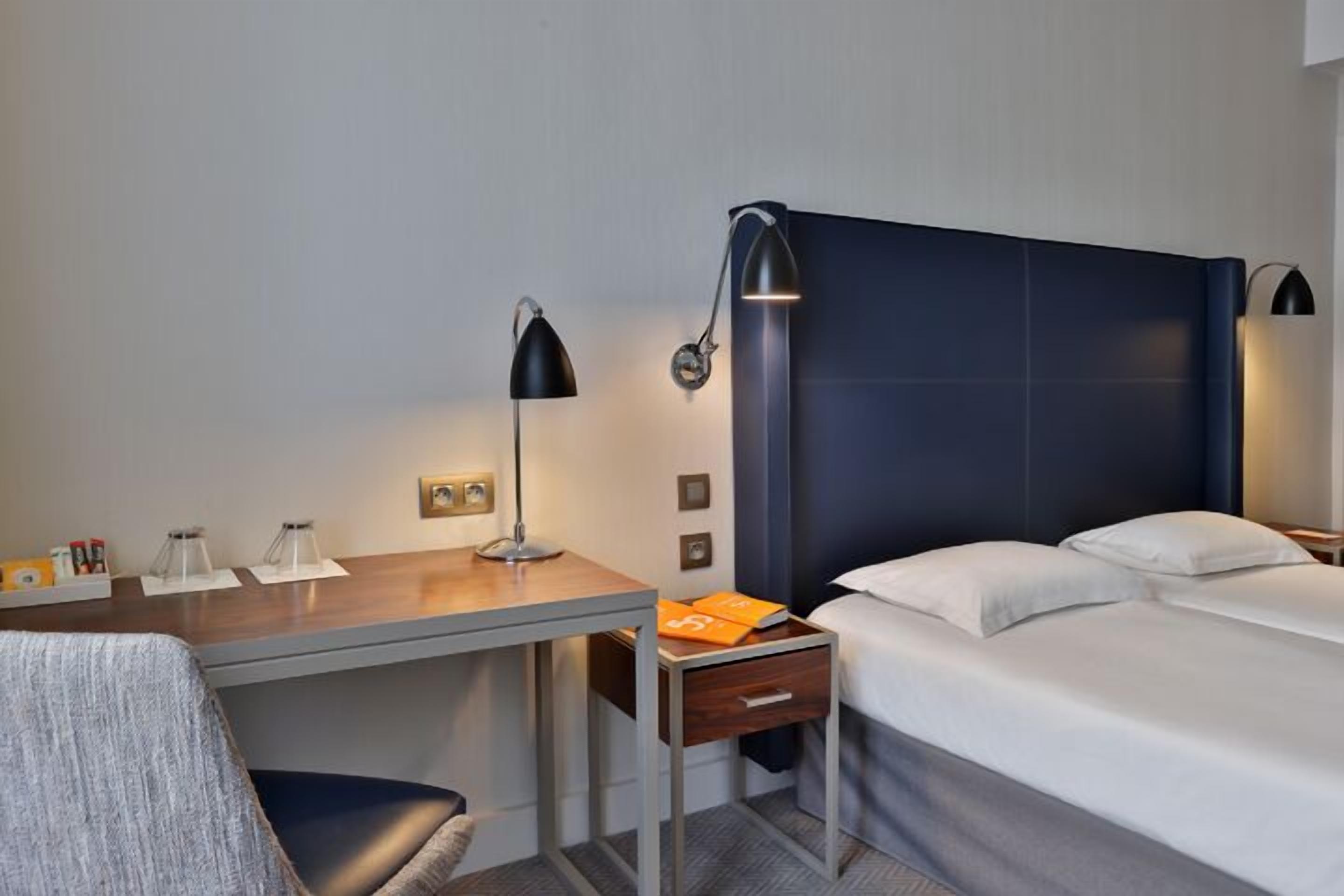 Ein Hotelzimmer mit Bett, Schreibtisch, Stuhl und Nachttisch.