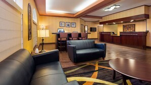 A hotel lobby with leather sofas, a reception desk, and a carpeted floor.