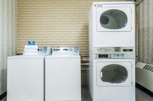 A laundry area with two stacked washing machines and a dryer.