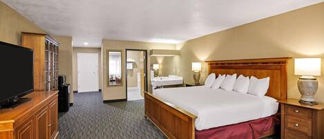 A hotel room with a bed, a television, a desk, and a bathroom visible through an open door.