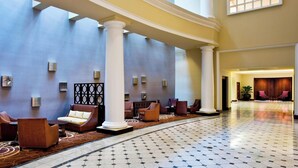 A spacious lobby with a curved floor, seating areas, and a large window providing natural light.