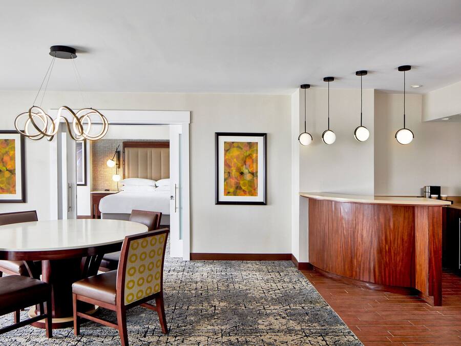 A hotel room with a dining area, a kitchen, and a bed.