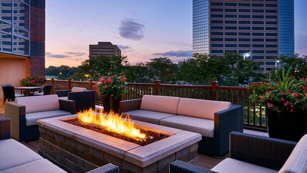 An outdoor seating area with a fire pit, cushioned seating, and potted plants.
