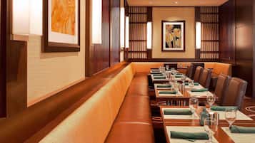 A restaurant with long wooden benches and tables, framed artwork on the walls, and a modern interior design.