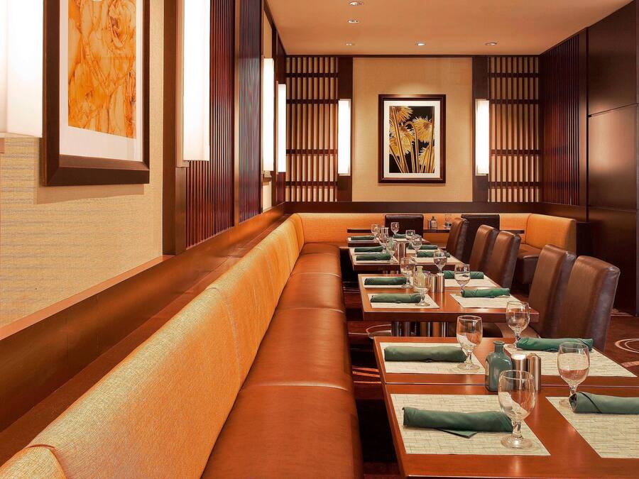 A restaurant with long wooden benches and tables, framed artwork on the walls, and a modern interior design.