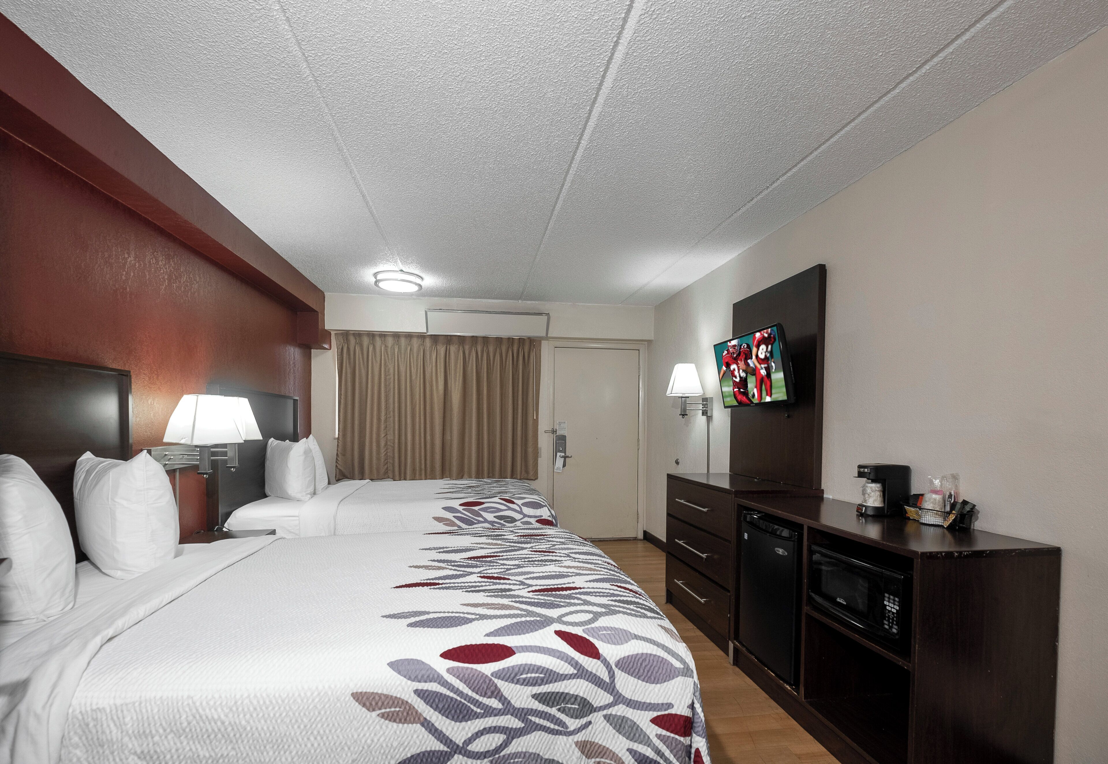 A hotel room with a large bed, a TV, a desk with a lamp, and a coffee maker.