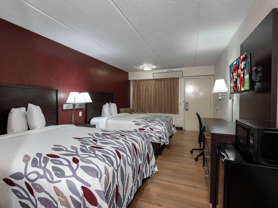 Una habitación de hotel con una cama grande, un escritorio, un televisor y un microondas.