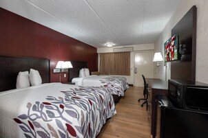 Una habitación de hotel con una cama grande, un escritorio, un televisor y un microondas.