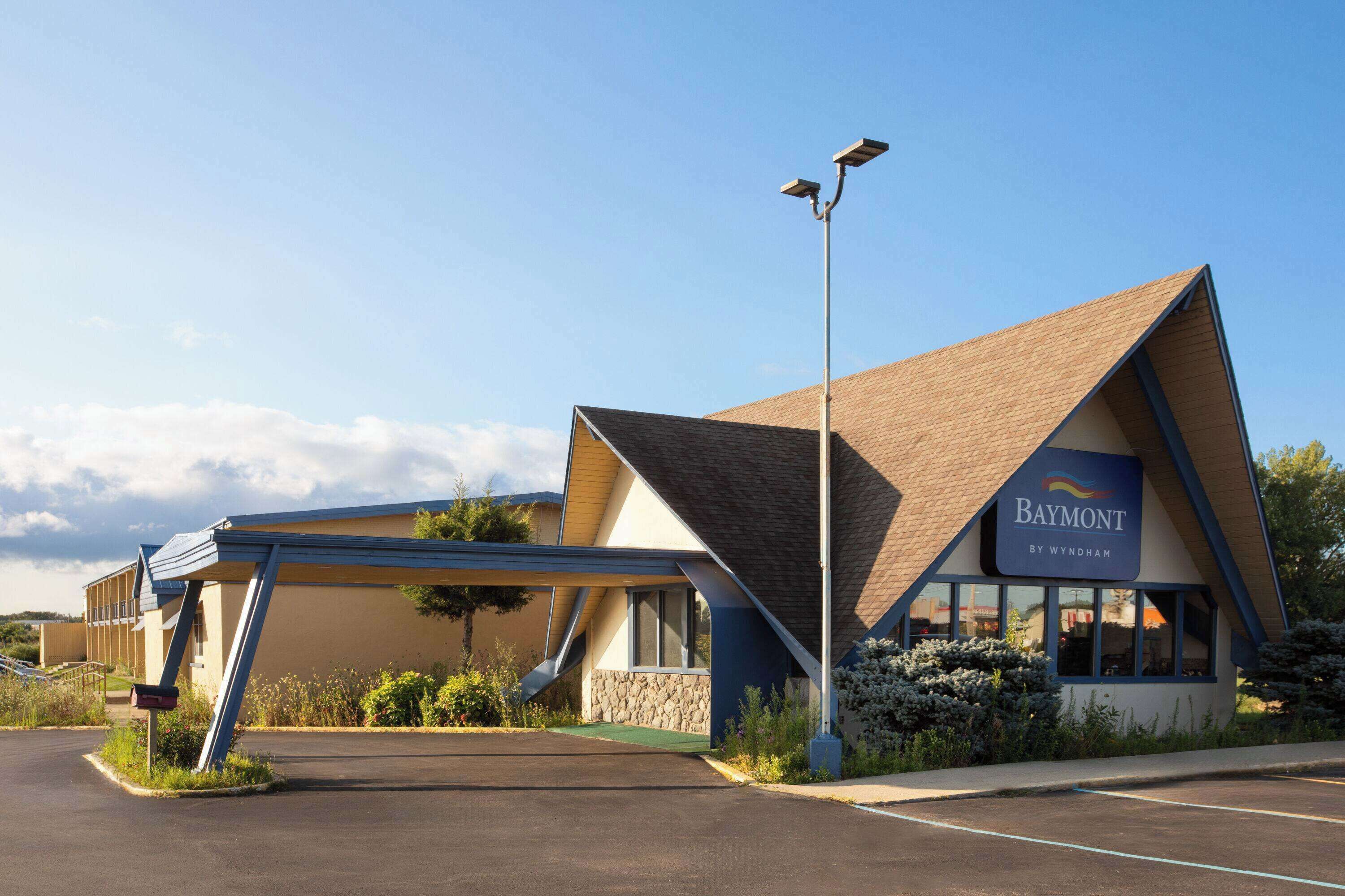A Baymont by Wyndham hotel with a modern design, including a sloped roof and a covered parking area.