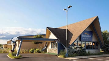A Baymont by Wyndham hotel with a modern design, including a sloped roof and a covered parking area.