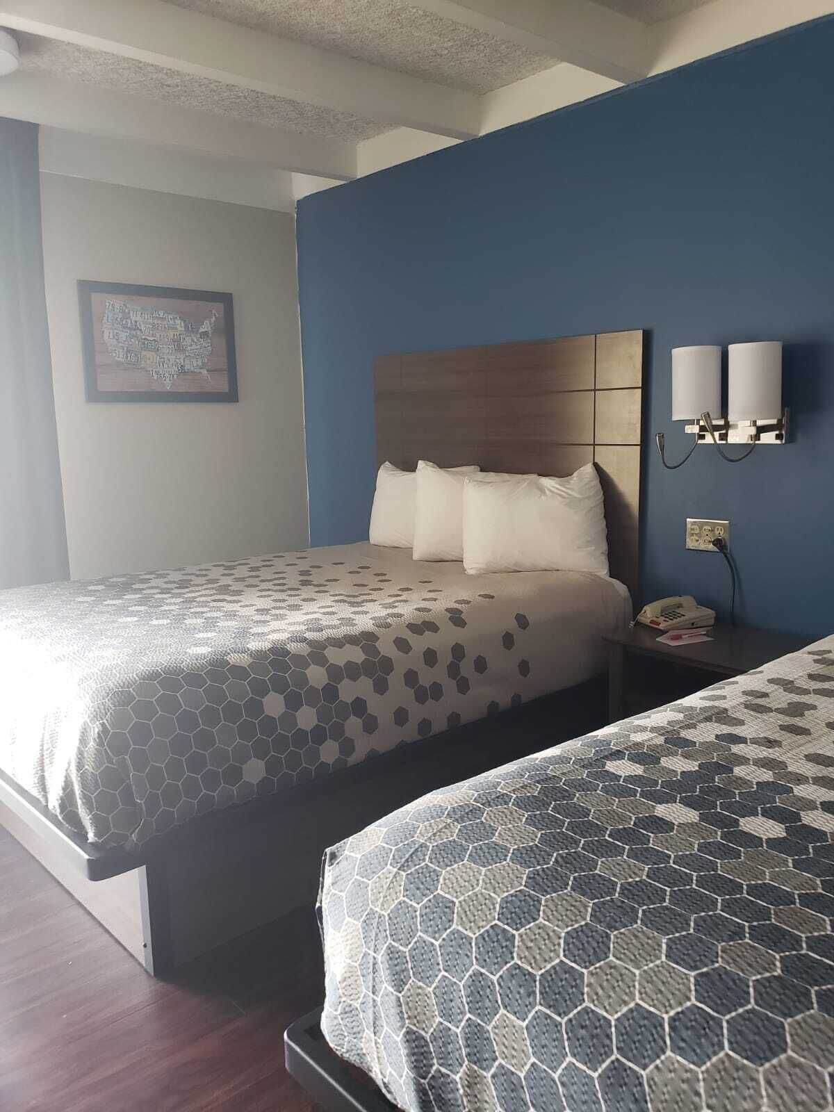 Habitación de hotel con dos camas, cabecero de madera, teléfono en la pared y un cuadro enmarcado.