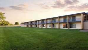 Un motel con una hilera de habitaciones, césped y cielo despejado.