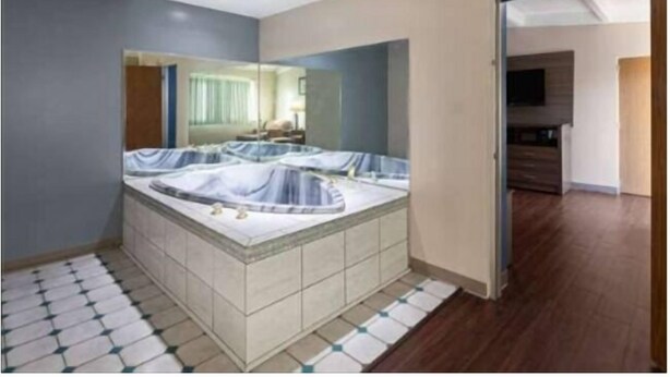 Un baño moderno con una bañera grande, un espejo y suelo de baldosas.