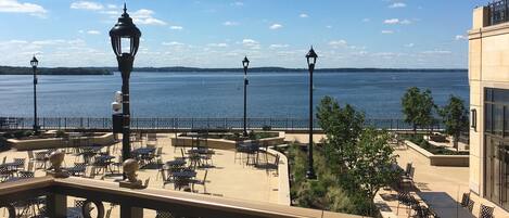 Une terrasse avec des sièges extérieurs donnant sur une étendue d’eau, un lampadaire et une vue sur l’eau.