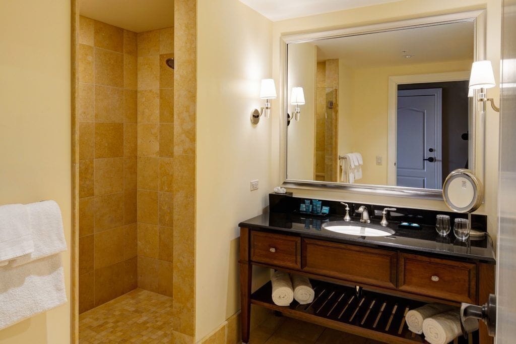 Ein Badezimmer mit Dusche, Waschbecken, Spiegel und Handtüchern.
